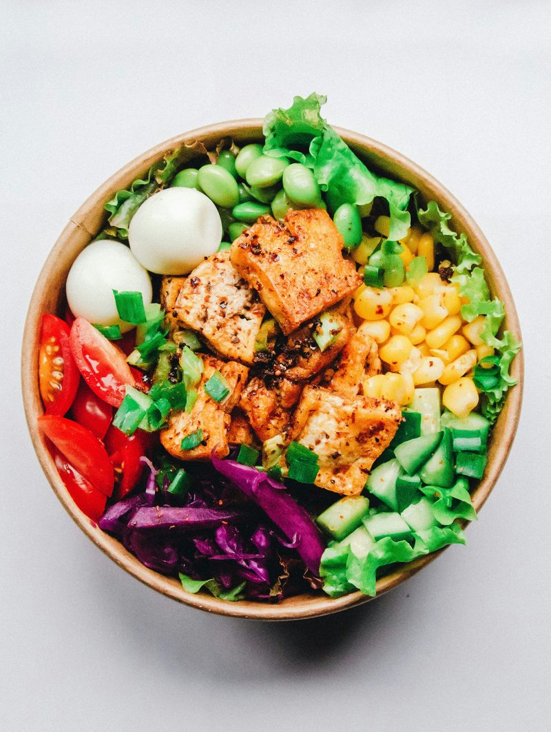 A bowl of greens, boiled eggs, sweetcorn, tomatoes and red cabbage