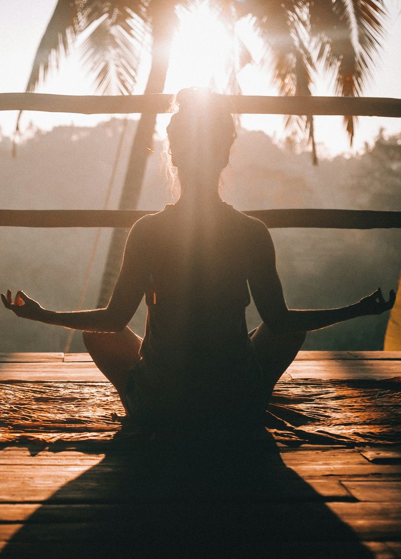 A woman meditating cross-legged at sunrise